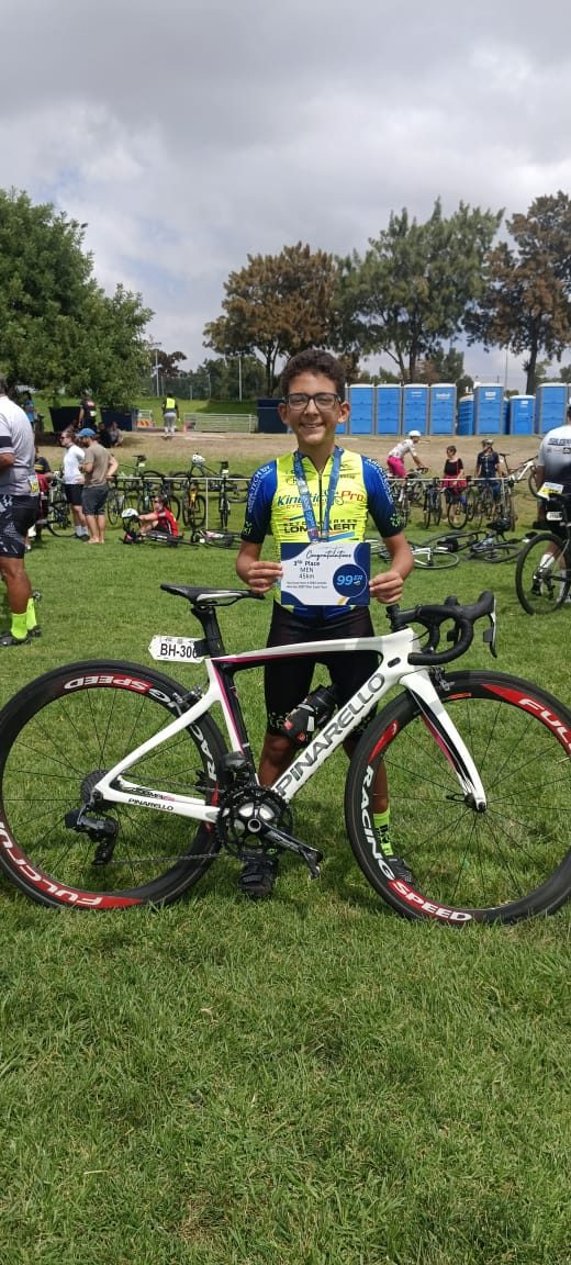 Youth rider with a medal standing next to a road bike